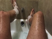 Pies y piernas de deportista jabonosos en la bañera